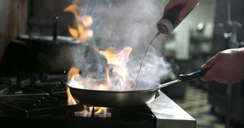 Squirting wine sauce and creating a huge flare up in kitchen Stock Footage 105377141