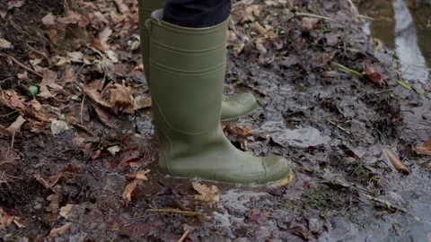 Squishy Green Rubber Boots Stepping Through Muddy Terrain Surrounded by Fallen Stock Footage 305197091