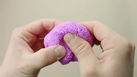 Squishy purple floam being squeezed in hands, showcasing texture and playful 動画素材 311839985