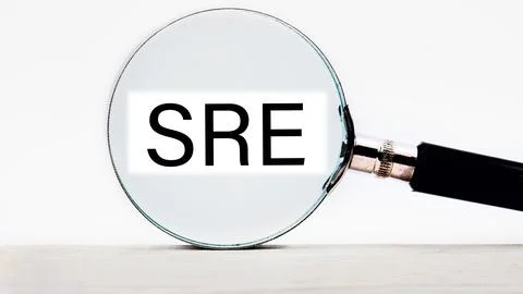 SRE. Site Reliability Engineering lettering on through a magnifying glass on  Stock Photos