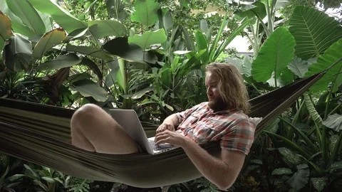 Сryptocurrency trader making bargain on laptop while lying on hammock Stock Footage 84817208