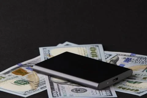 SSD external drive surrounded by dollar and euro notes in studio light Stock-Fotos