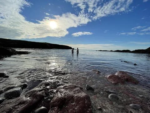 St Brides bay sun setting with people in the sea Stock Photos