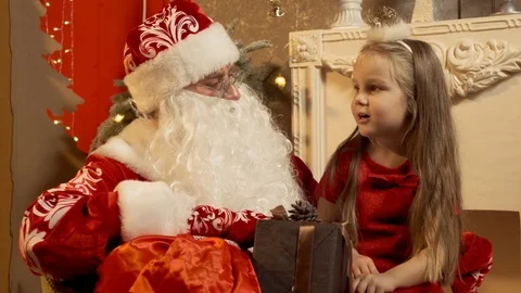 St Nicholas gets present out of the bag and gives it to little girl in slow Video stock 100027154
