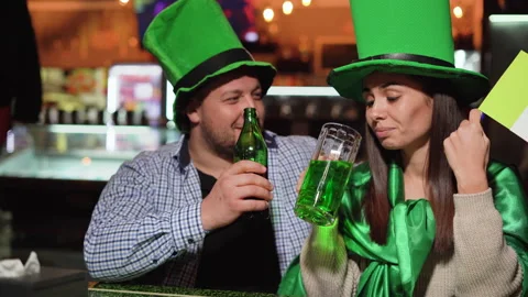 St. Patrick's Day, a man and a woman are sitting in a pub drinking beer big Stock Footage 147577571