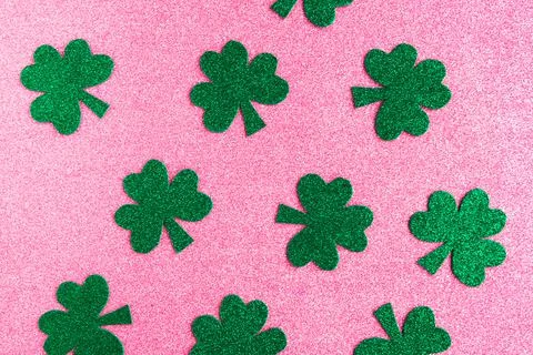 St. Patrick's Day pattern paper shamrocks on pink glitter background. Stock Photos