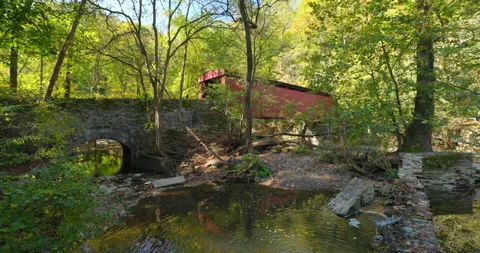 Stabilized Gimbal Shot Red Covered Bridge in woods with Creek and Waterfall Vidéo 141960645