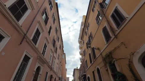 Stabilized low-to-high forward walk along city street with yellow and pink build Stock Footage 322117299