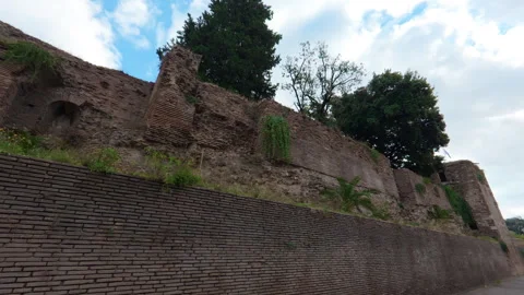 Stabilized low left-to-right walk past ancient Roman brick wall by city street Stock Footage 322114627