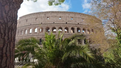 Stabilized right-to-left walk of Colosseum main facade with trees in foreground Stock Footage 322111680