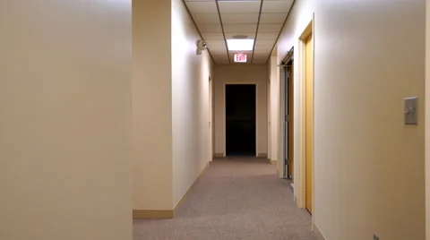 Stabilized shot moving down commercial hallway towards dark room Stock Footage 59565076