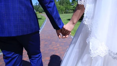 Stabilizer, close-up, bride and groom walking in the park holding hands Video stock 99365884
