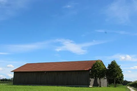 Stable in the open with two trees and a cross. Stock Photos