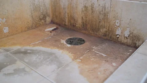 Stable pan shot from right to left of unclean floor and wall of bathroom Stock Footage 158319691