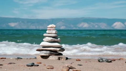 Stable stacks of pyramids of stones, waves seawater breaking on shore. closeup. Stock Footage 252195554