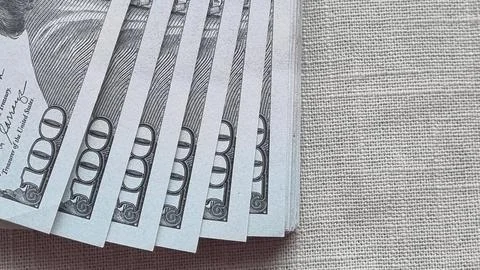 Stack of 100 US dollar bills fanned out on textured fabric surface Stock Photos