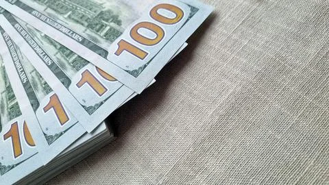 Stack of 100 US dollar bills fanned out on textured beige fabric background Stock Photos