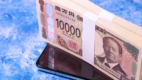 Stack of 10,000 yen bills and smartphone, rotating. Video stock 304254037