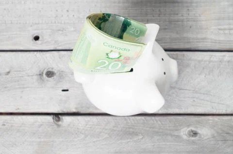 Stack of 20 dollars bill stuck at the opening slot of a white piggy bank Stock Photos