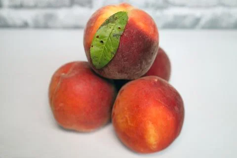 A stack of 4 peaches with a leaf on the top peach Stock Photos