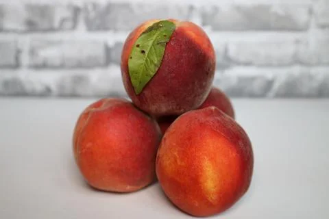 A stack of 4 peaches with a leaf on the top peach Stock Photos