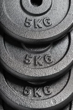 Stack of 5kg barbell / dumbbell weight plates inside a weightlifting gym Stock Photos