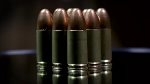 A stack of 9mm bullets with reflection on the glass plate of rotating table. Stock Footage 263047092