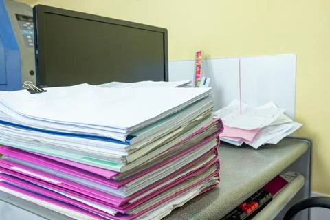 Stack of accounting documents with computer screen on desk Stock Photos