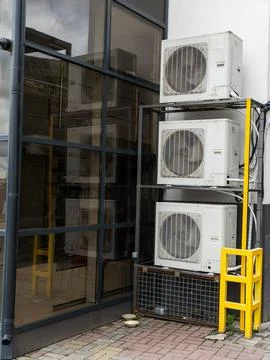 A stack of air conditioners sitting on top of each other in front of a building Stock Photos