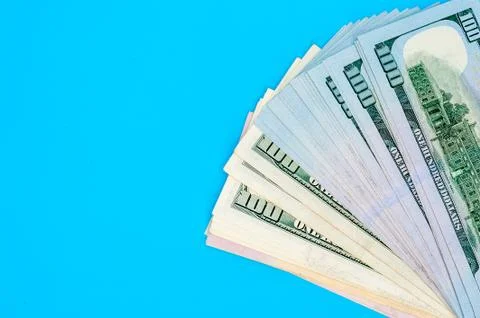 Stack of american dollar bills on blue background. Stock Photos