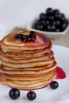 Stack of american pancakes with blackcurrant jam and blackcurrant berries. Stock Photos