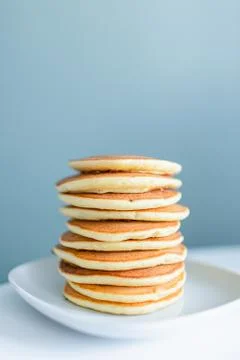 Stack of american pancakes on a white table on blue background. Copyspace. Br Stock Photos