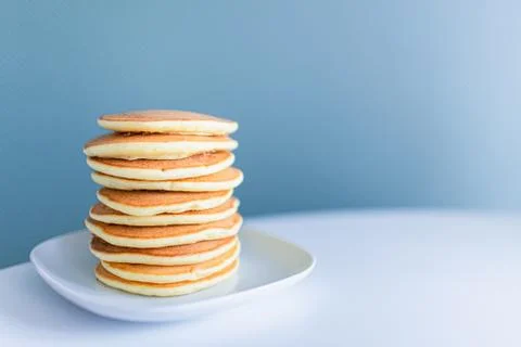 Stack of american pancakes on a white table on blue background. Copyspace. Br Stock Photos