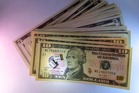 A stack of american ten and five dollar bills with dice on the foreground Stock Photos