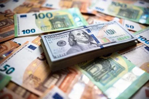 A stack of American USD dollars hundreds bills is on top of euro money banknotes Stock Photos