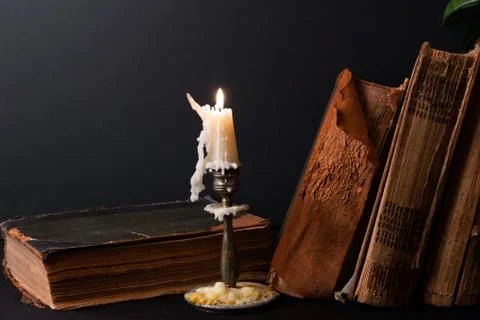 Stack of ancient books and lighted candle Stock Photos