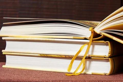 Stack of ancient books with one opened book above the heap on the bookshelf 写真素材