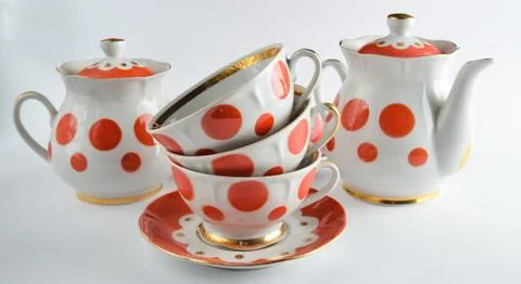 Stack of antique ceramic cups on a saucer, teapots, sugar bowls on a white ba Stock Photos