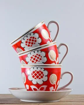 Stack of antique ceramic cups on a wooden table against a white wall Stock Photos