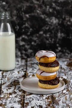 Stack of assorted donuts on a white plate with bottle of milk. Chocolate donu Stock Photos