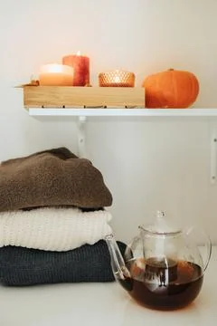 A stack of autumn sweaters next to warm tea and candles. Autumn mood Stock Photos