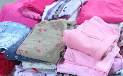 Stack of baby clothes in pink and postel colors. Cleaning and recycling. Ecology Stock Photos