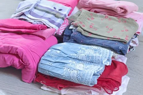 Stack of baby clothes in pink and postel colors. Cleaning and recycling. Ecology Stock Photos