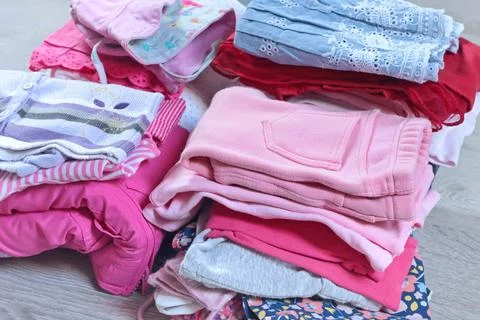 Stack of baby clothes in pink and postel colors. Cleaning and recycling. Ecology Stock Photos