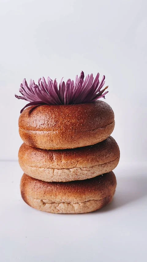 Stack of bagels with a purple flower on top  against a white background Stock Footage 273269256
