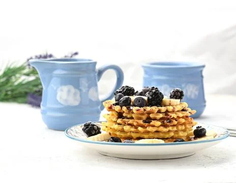 Stack of baked Belgian waffles on a round plate with berries on a white table Stock-Fotos