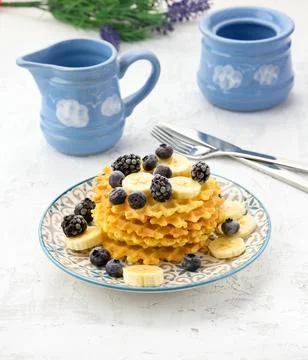Stack of baked Belgian waffles on a round plate with berries on a white table Stock Photos