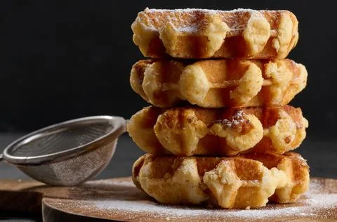 A stack of baked Belgian waffles sprinkled with powdered sugar Foto stock