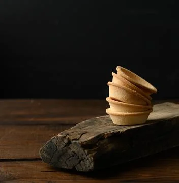 Stack of baked round blank tartlets on wooden board, black background Stockfoto's