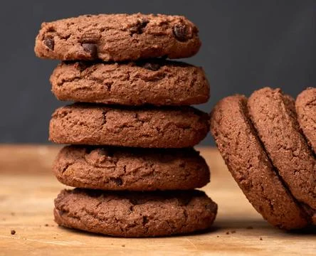Stack of baked round chocolate chip cookies on a brown wooden table stack ... Stock-Fotos